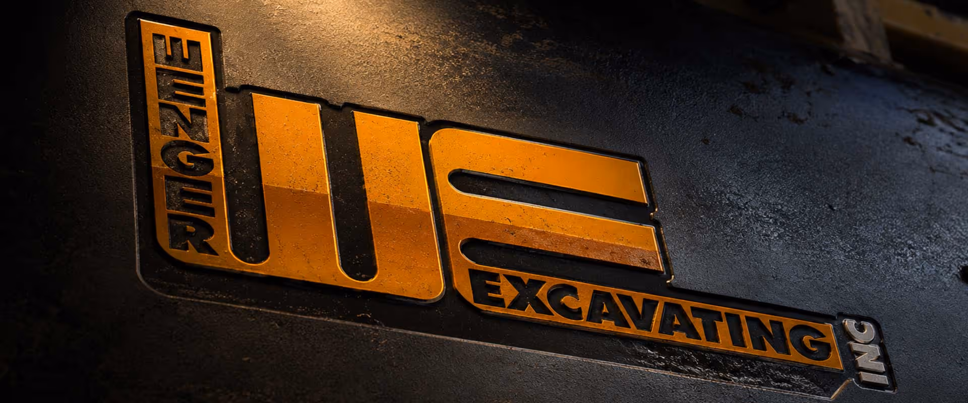 Wenger Excavating logo displayed on industrial equipment surface with dramatic lighting, representing more than 45 years of excavation and site development experience.