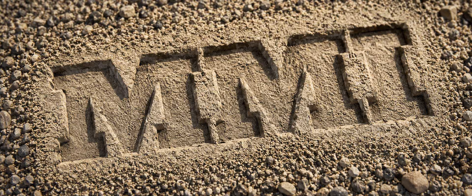 Massillon Materials logo carved into a sand and gravel surface representing aggregate production and construction materials.