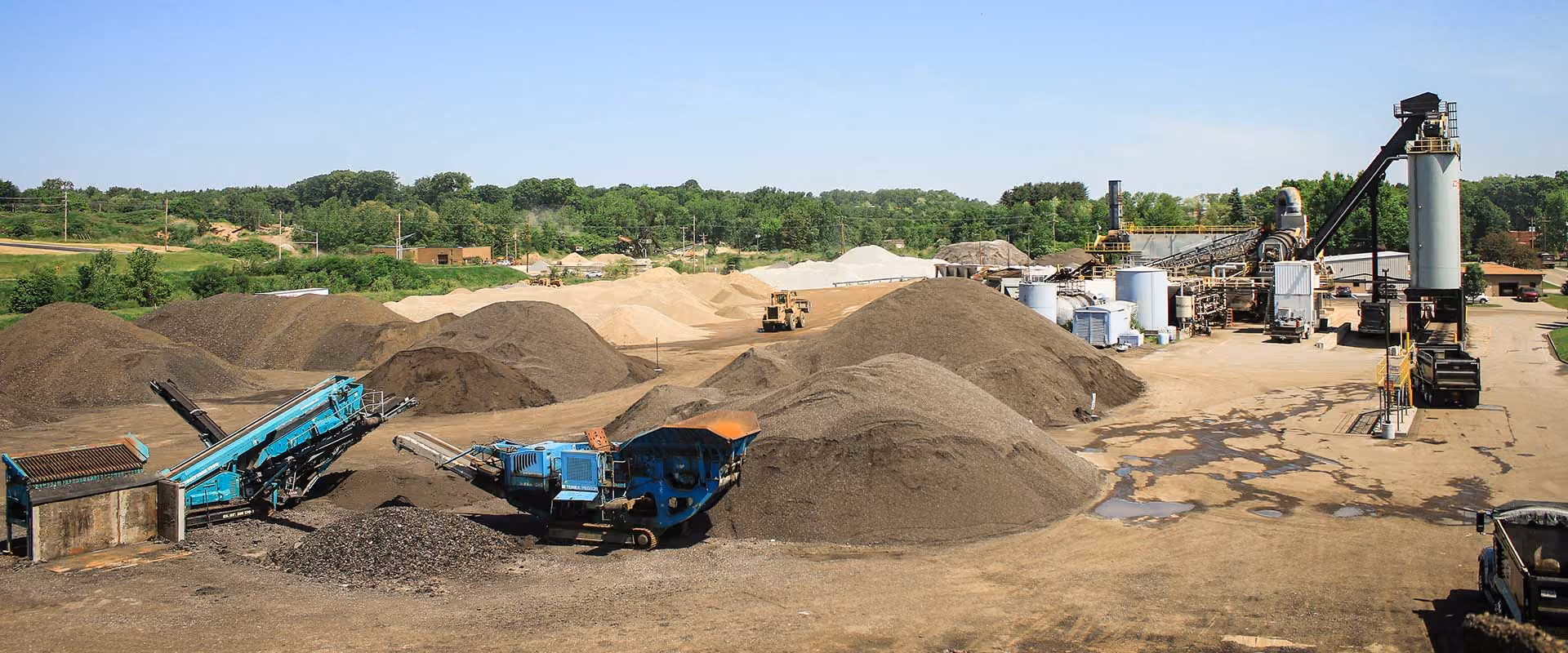 Aerial view of the Massillon Materials production facility featuring aggregate stockpiles, asphalt manufacturing equipment, and loading operations.