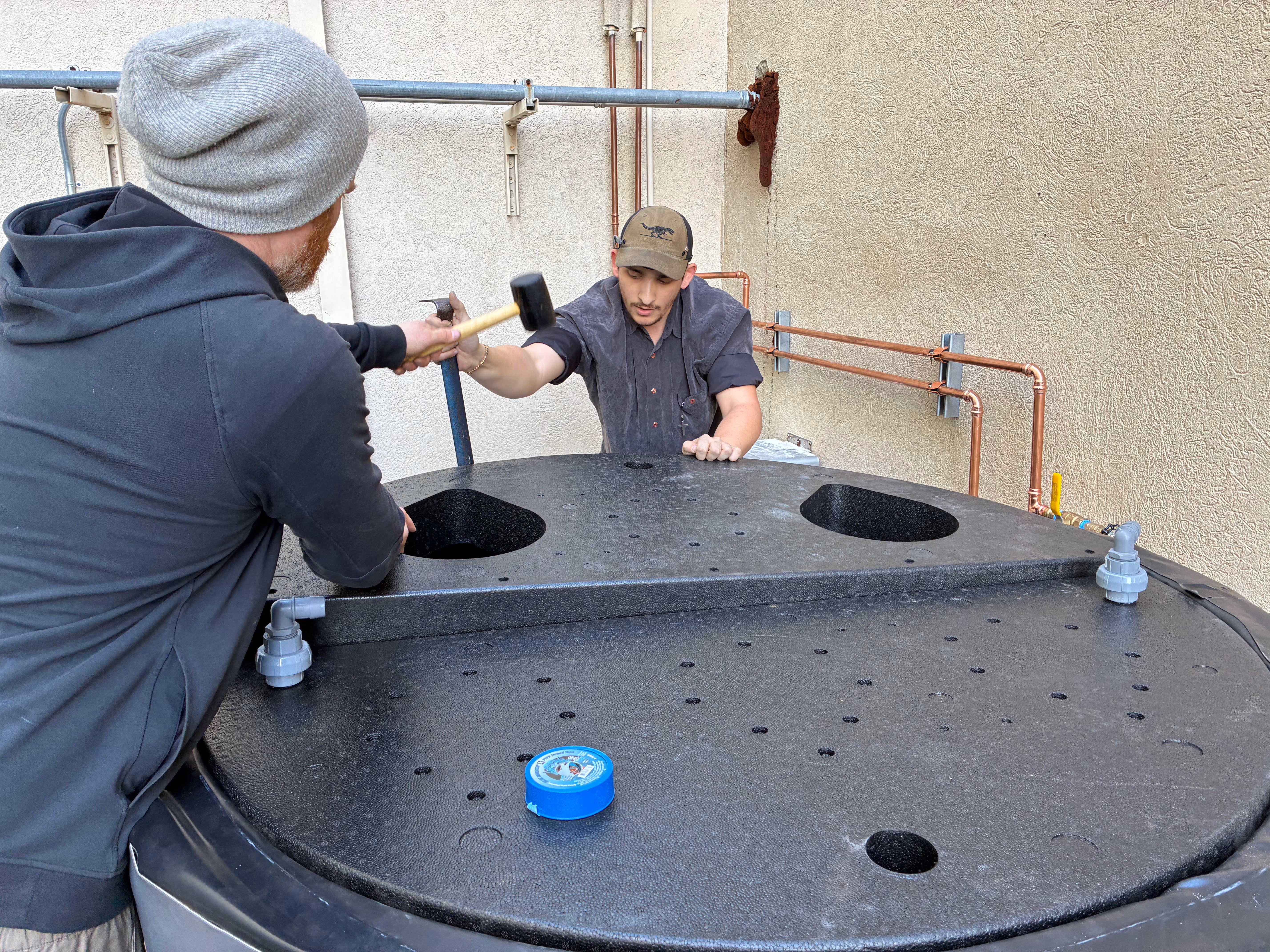 Two workers building a thermal tank.