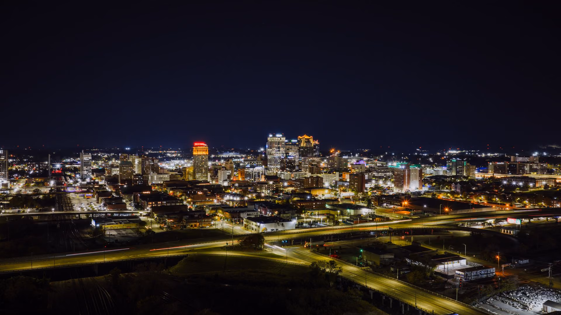 Stunning aerial night view of Birmingham, Alabama skyline with city lights.