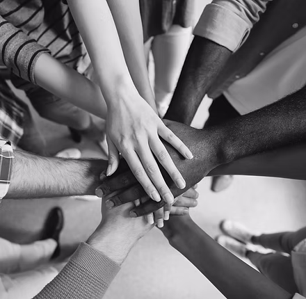 Diverse group of people stacking hands together in a circle symbolizing unity and teamwork.