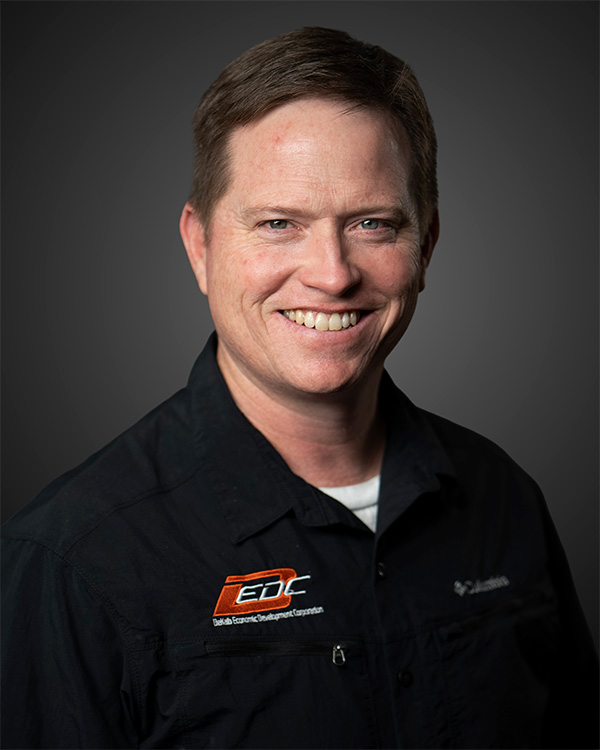 Smiling man in black shirt with Delta Economic Development Corporation logo on chest.
