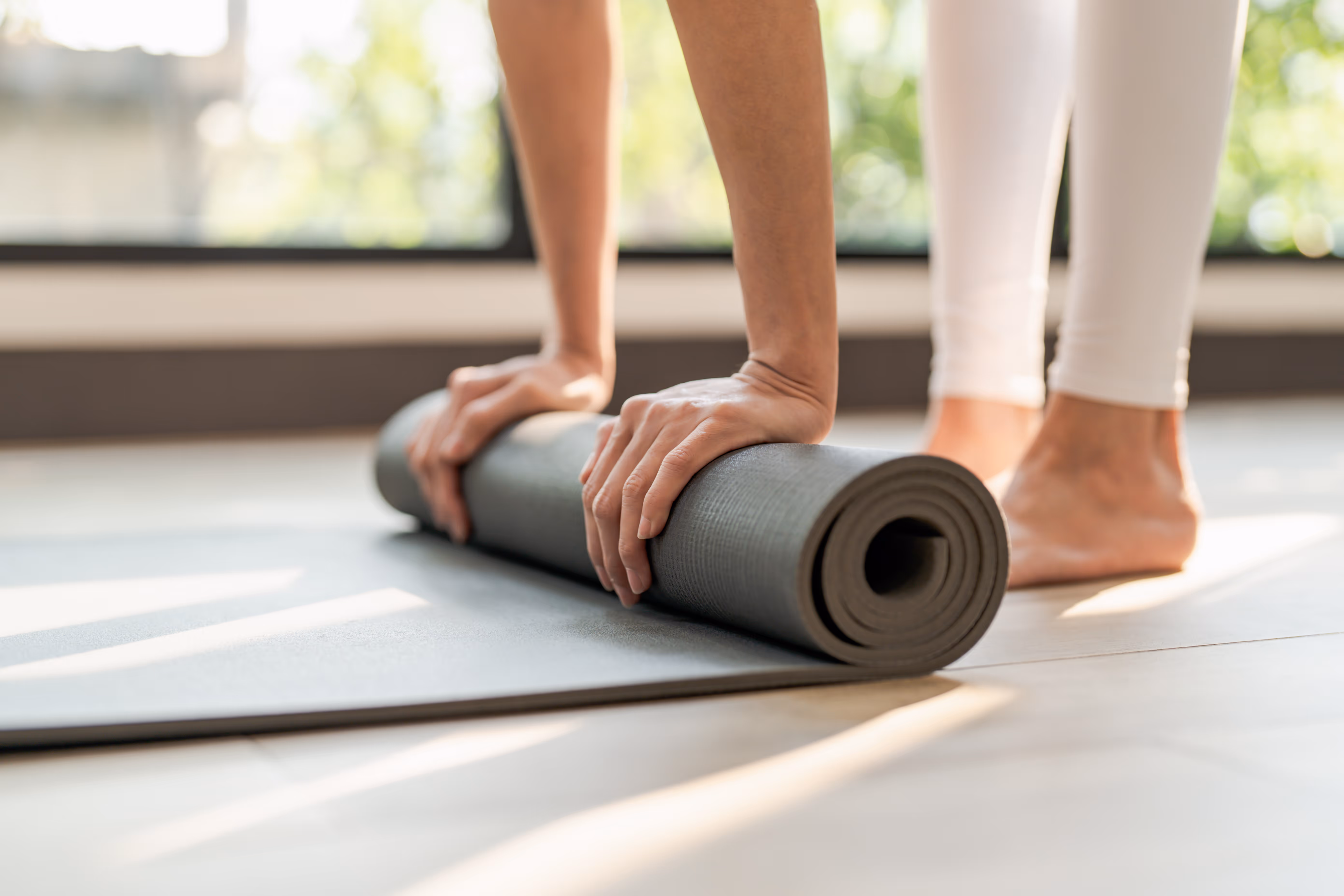 Woman rolling up yoga mat stock image