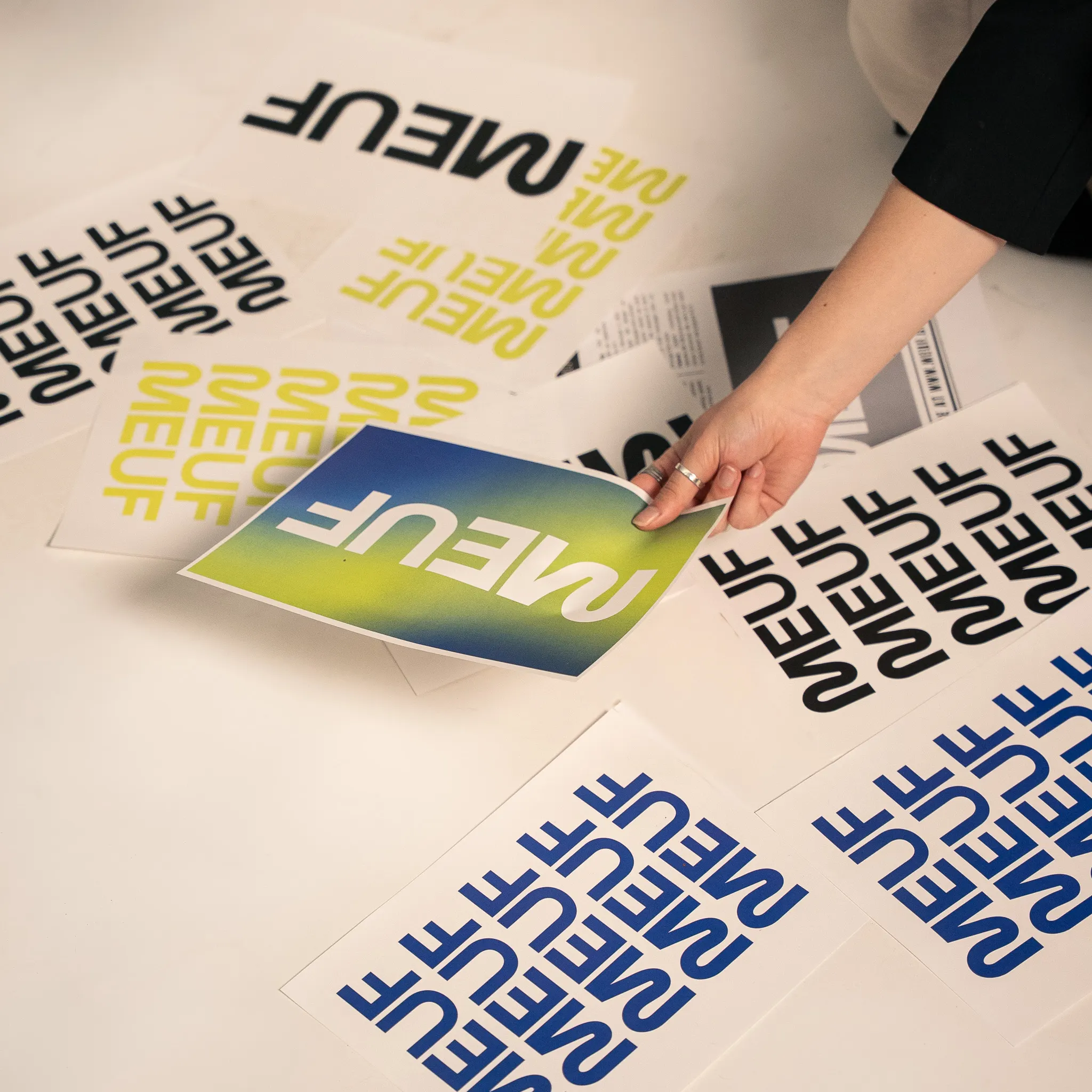 Affiches typographiques de la marque MEUF disposées à la main, en bleu et jaune-vert