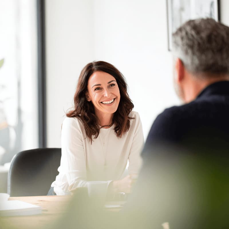 A woman smiling and having a conversation with a coworker in an office