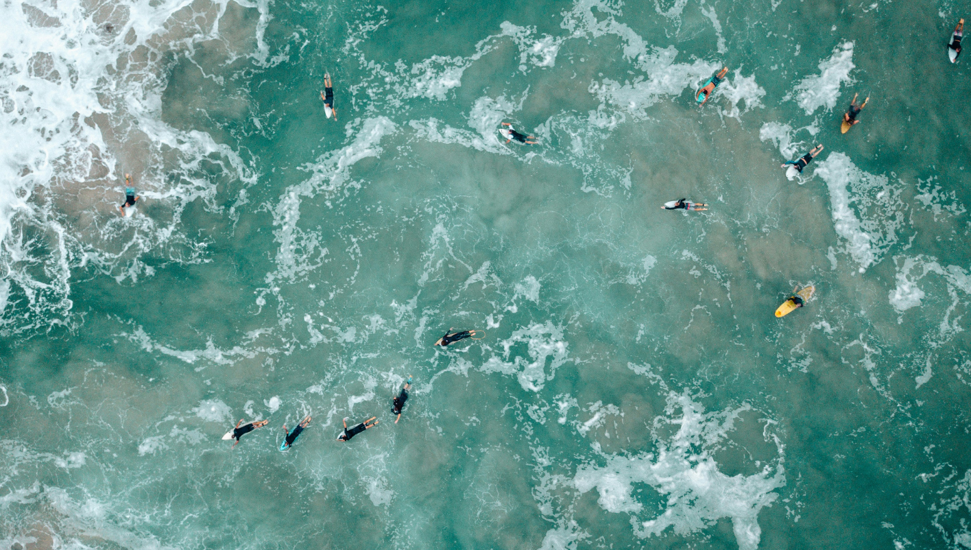 People surfing in the ocean, riding waves on surfboards.
