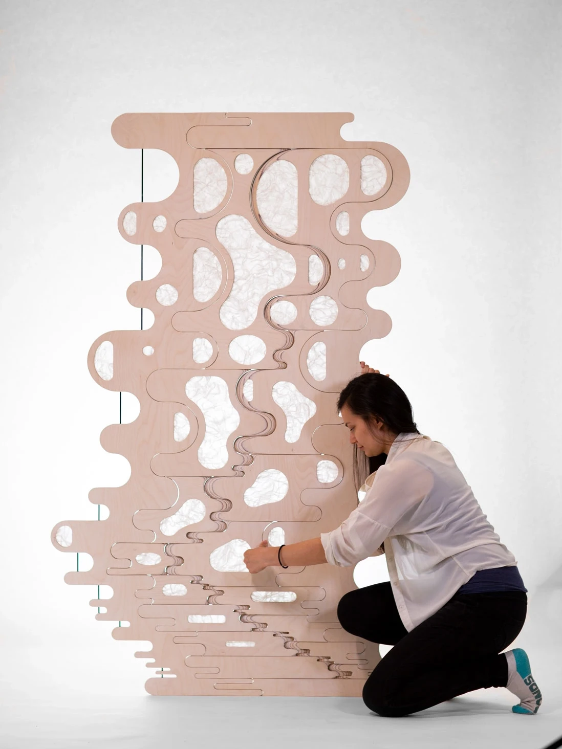 Designer holding timber screen in closed configuration to demonstrate form
