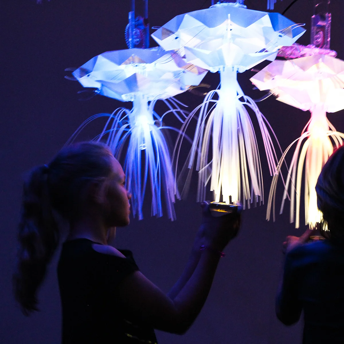 Two children interacting with a glowing jellyfish-inspired light installation