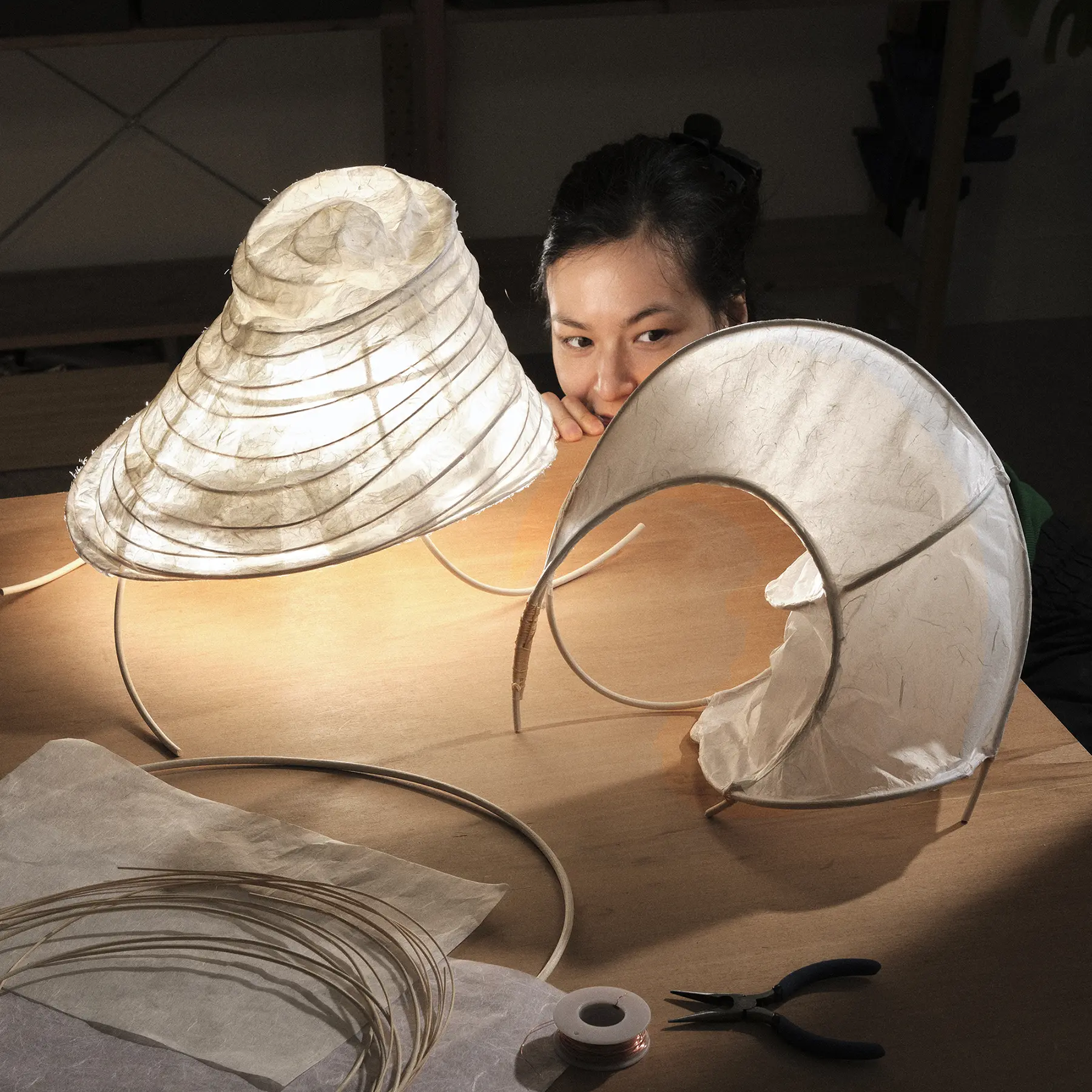 Designer examining handmade paper lantern prototypes on a worktable.
