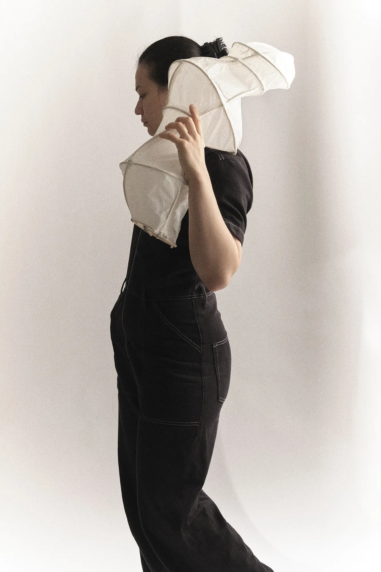 Designer holding an organic-shaped handmade paper lantern against a white background.