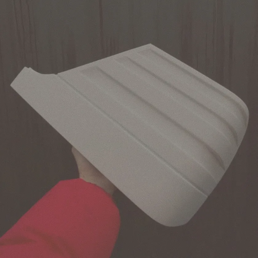Hand hält ein graues segmentiertes Kunststoffteil vor einem dunklen holzvertäfelten Hintergrund.