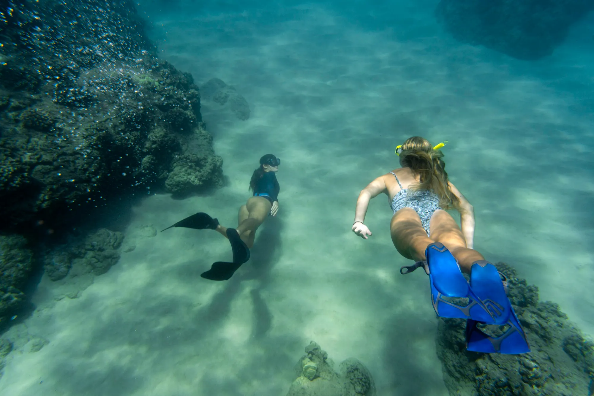 women freediving with flippers underwater