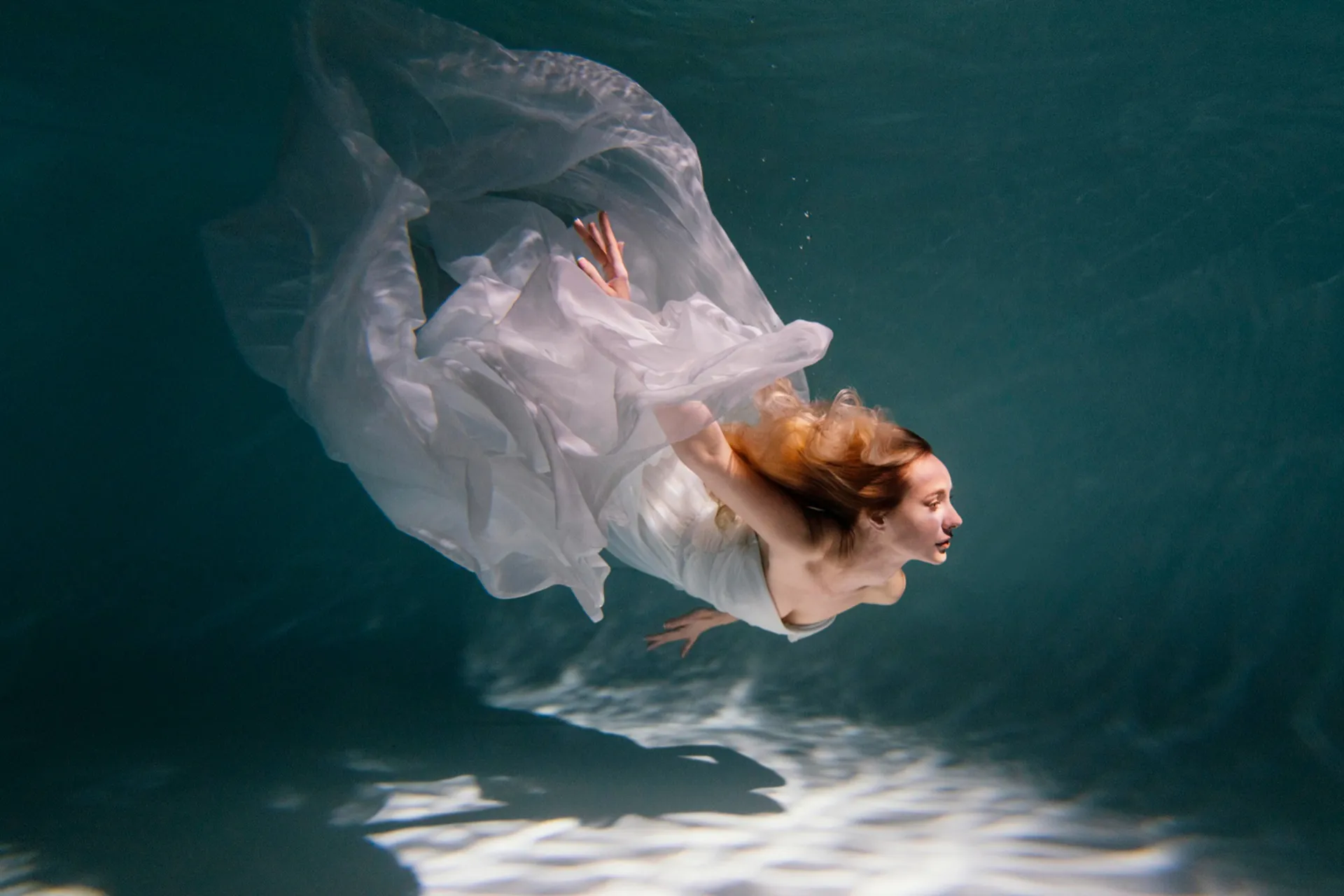 young woman posing submerged underwater flowy dress