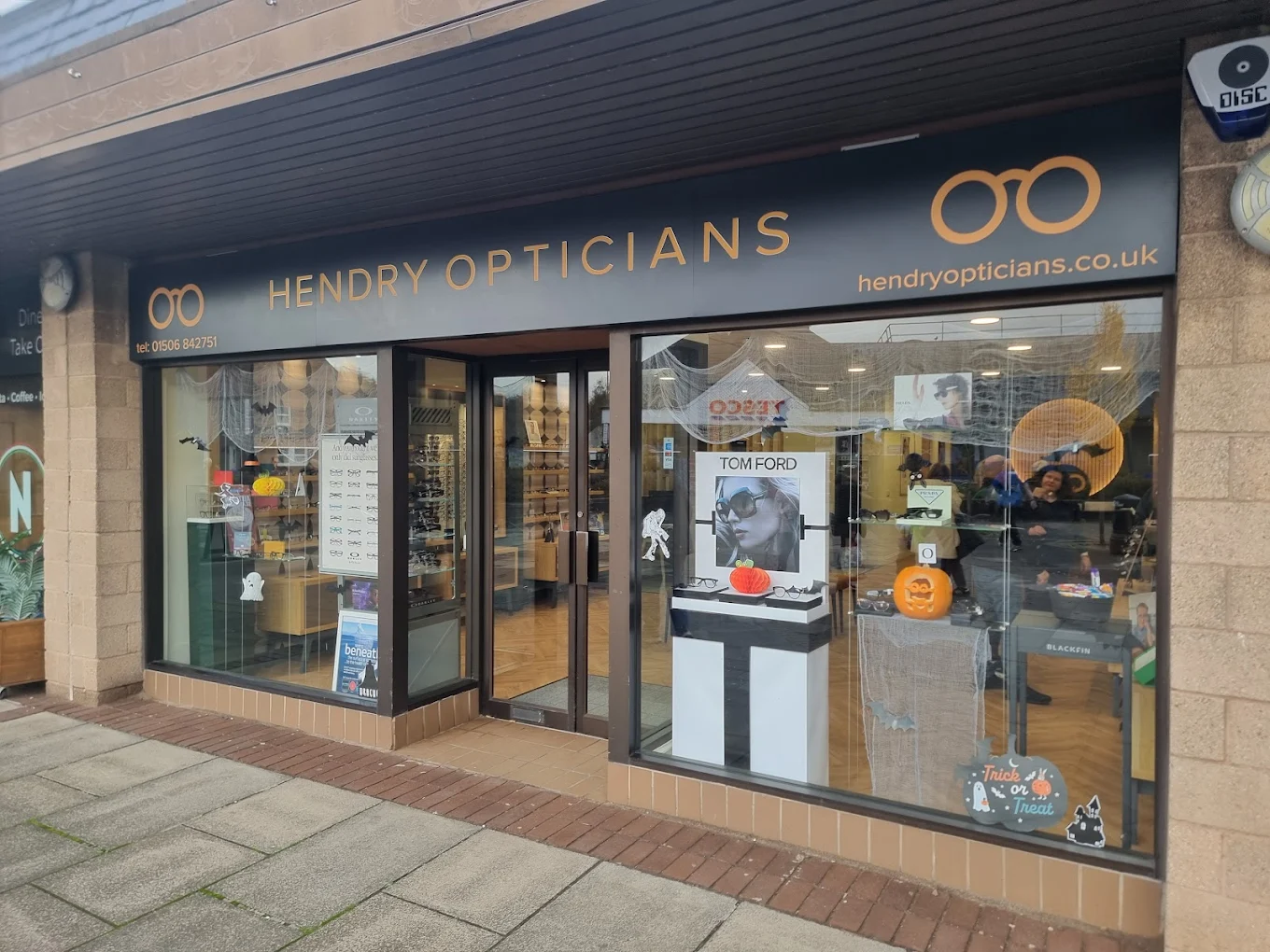 Hendry Opticians storefront decorated with Halloween pumpkins, ghosts, bats, and sunglasses displays.