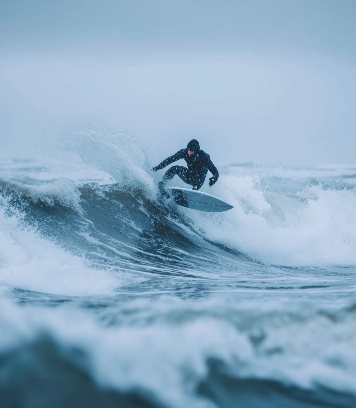 Woman in a red and black wetsuit standing waist-deep in calm water with hands behind her head.