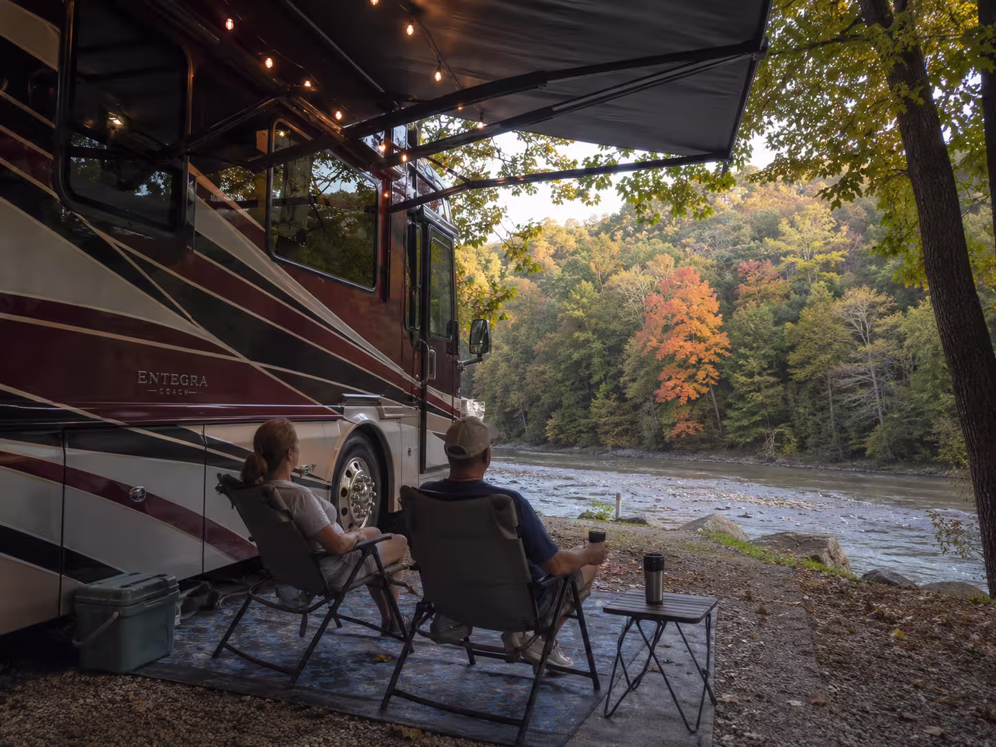 Couple relaxing beside a luxury RV at a riverside RV park near Asheville