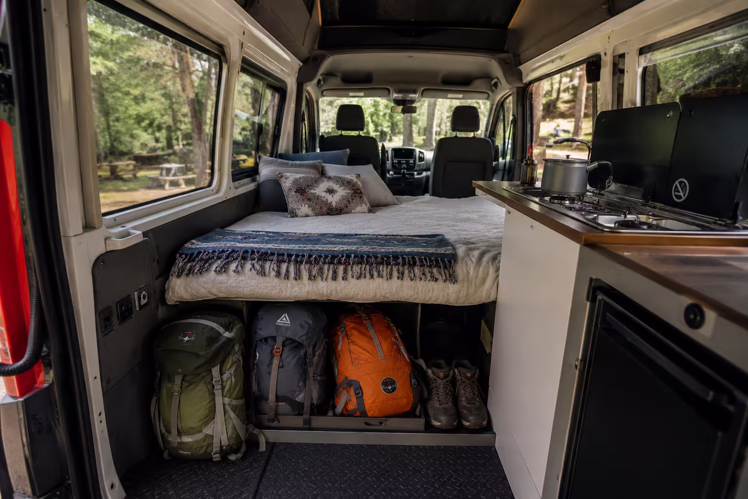 Camper van interior with convertible bed and gear storage near Asheville