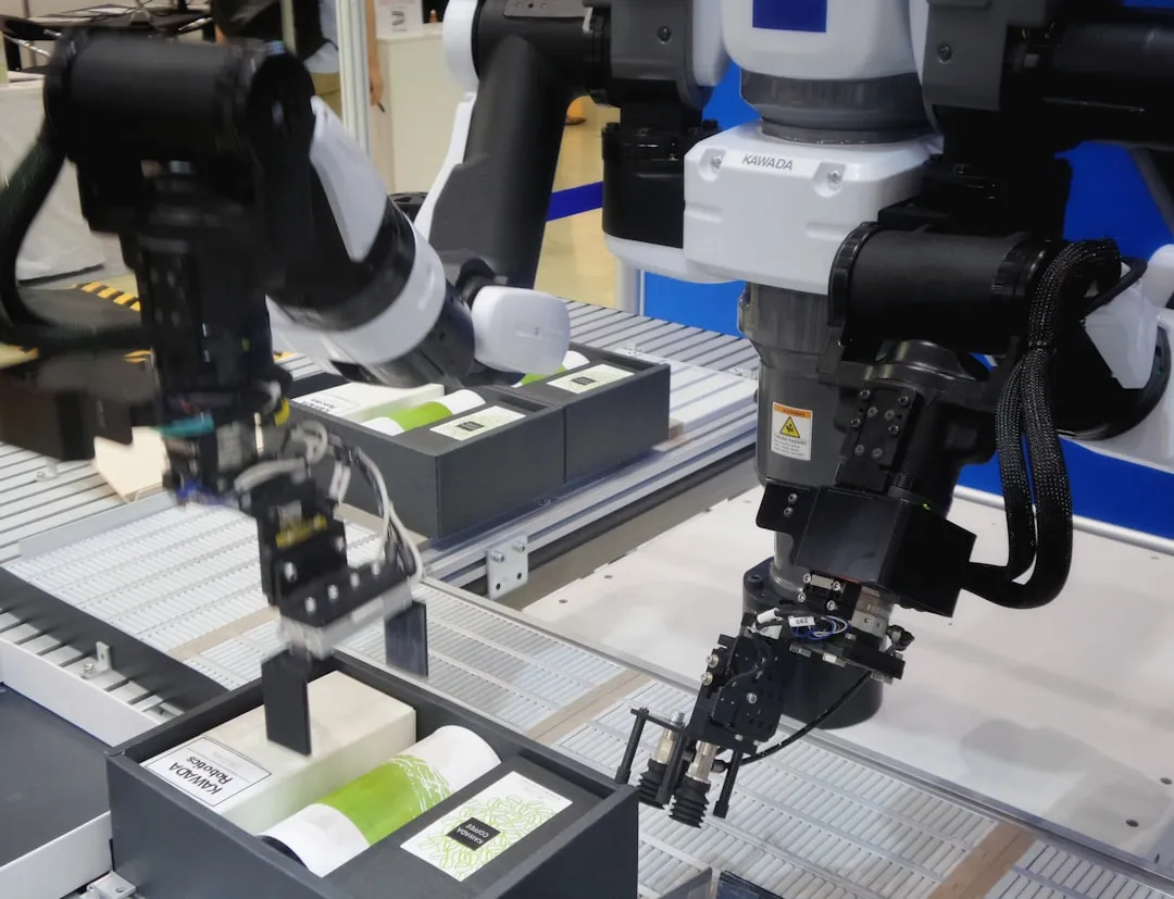 Industrieroboter mit Greifarmen verpacken weiße und grüne Flaschen in schwarze Kisten.