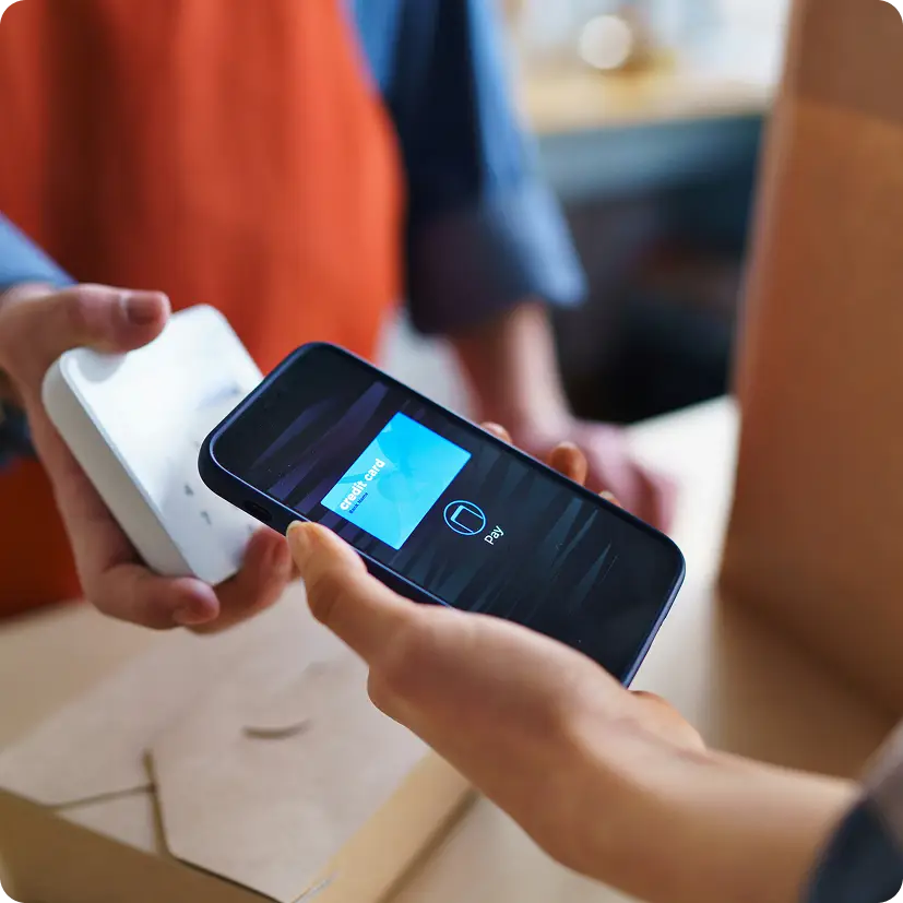 Person holding smartphone with digital credit card near payment terminal for contactless pay.