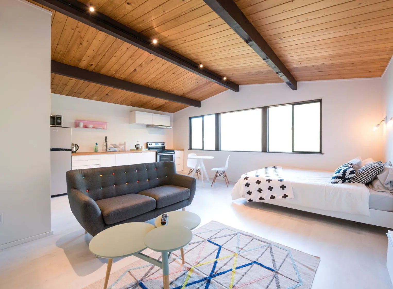 Modern living room with built-in shelving and cabinets, a stone fireplace with a mounted TV, a dark wooden coffee table, and a light sectional sofa with decorative pillows.