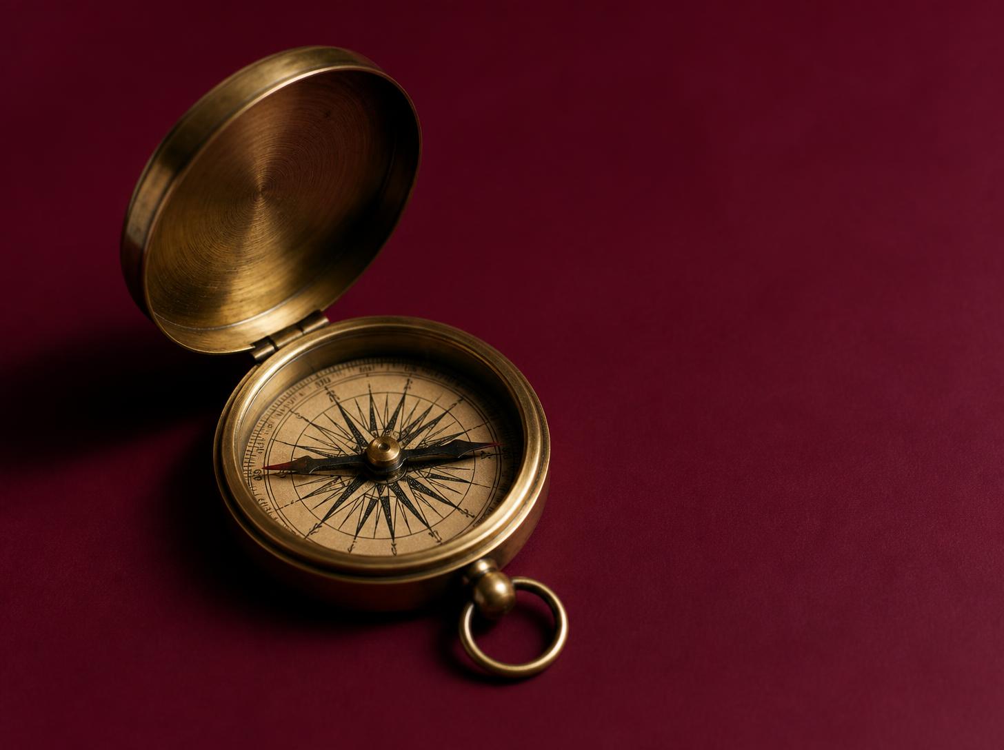 Brass compass on a burgundy surface