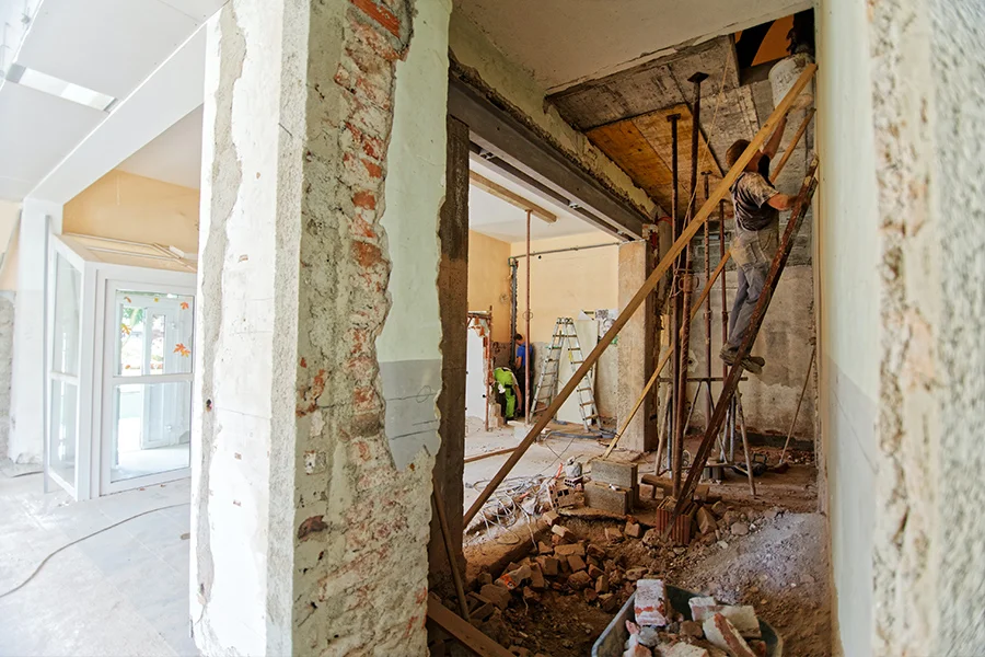 Innenraum im Rohbau mit offenen Wänden, Baustützen und laufender Sanierung im Bestand
