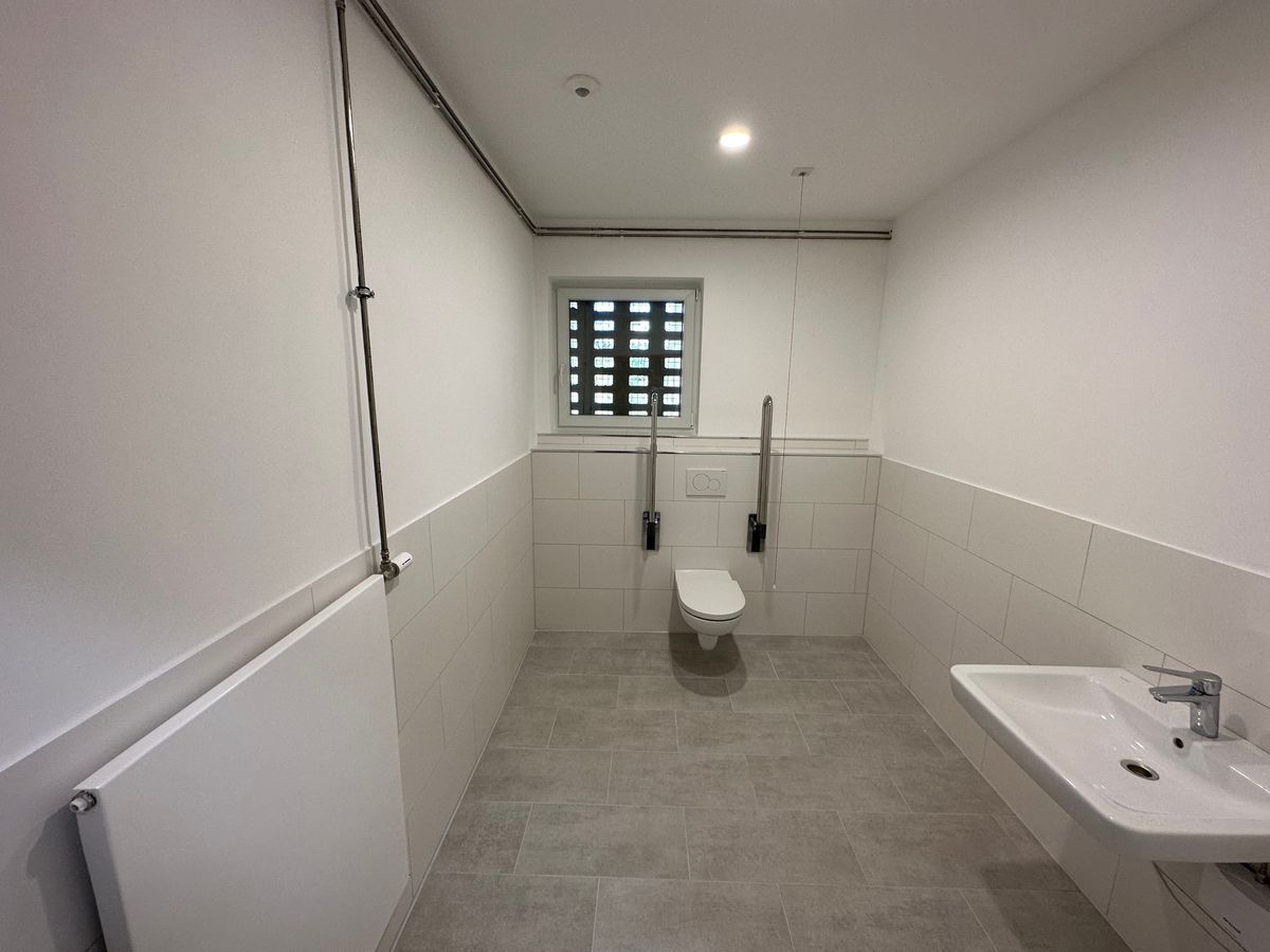 Barrierefreies Badezimmer mit ebener Bodenfläche, WC, Waschtisch und viel Bewegungsfreiheit