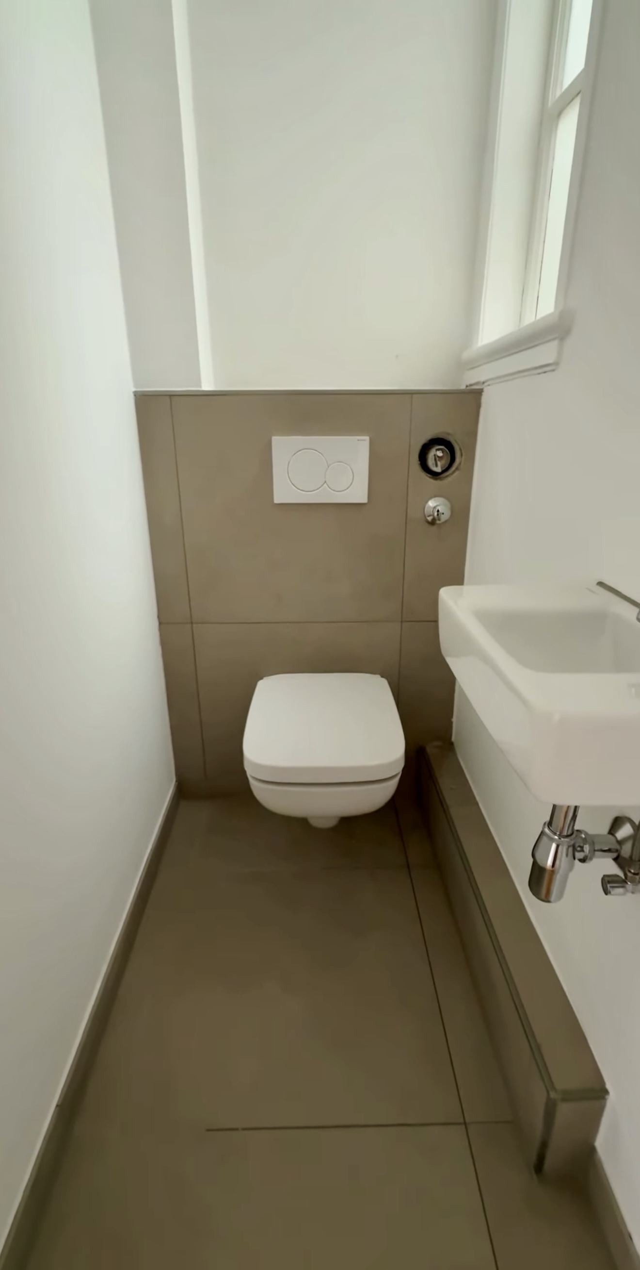Modernisiertes Gäste-WC mit wandhängendem WC, hellen Wänden und sauber verlegtem Boden