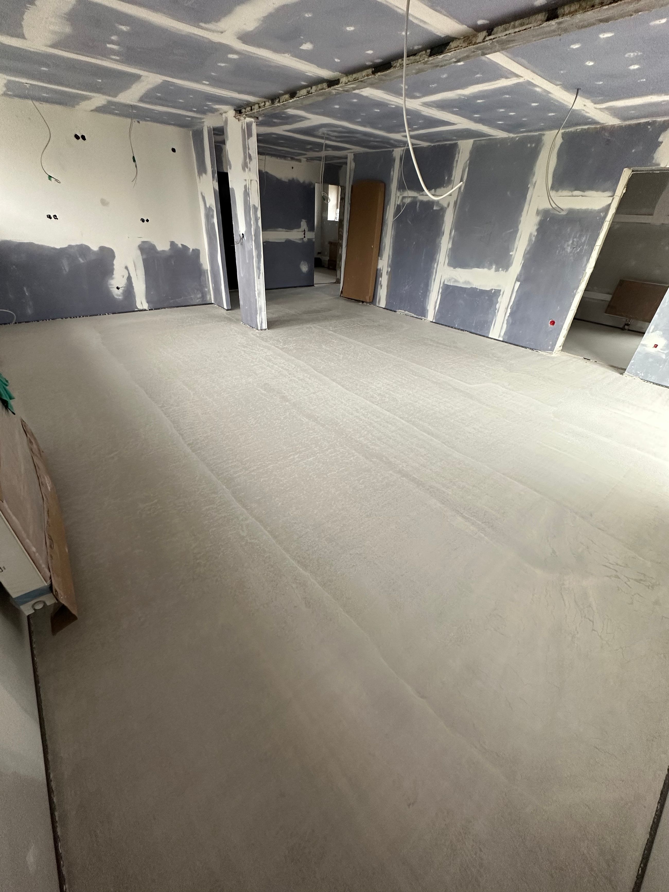 Großer Innenraum während Trockenbauarbeiten mit vorbereiteten Deckenflächen und Bodenaufbau