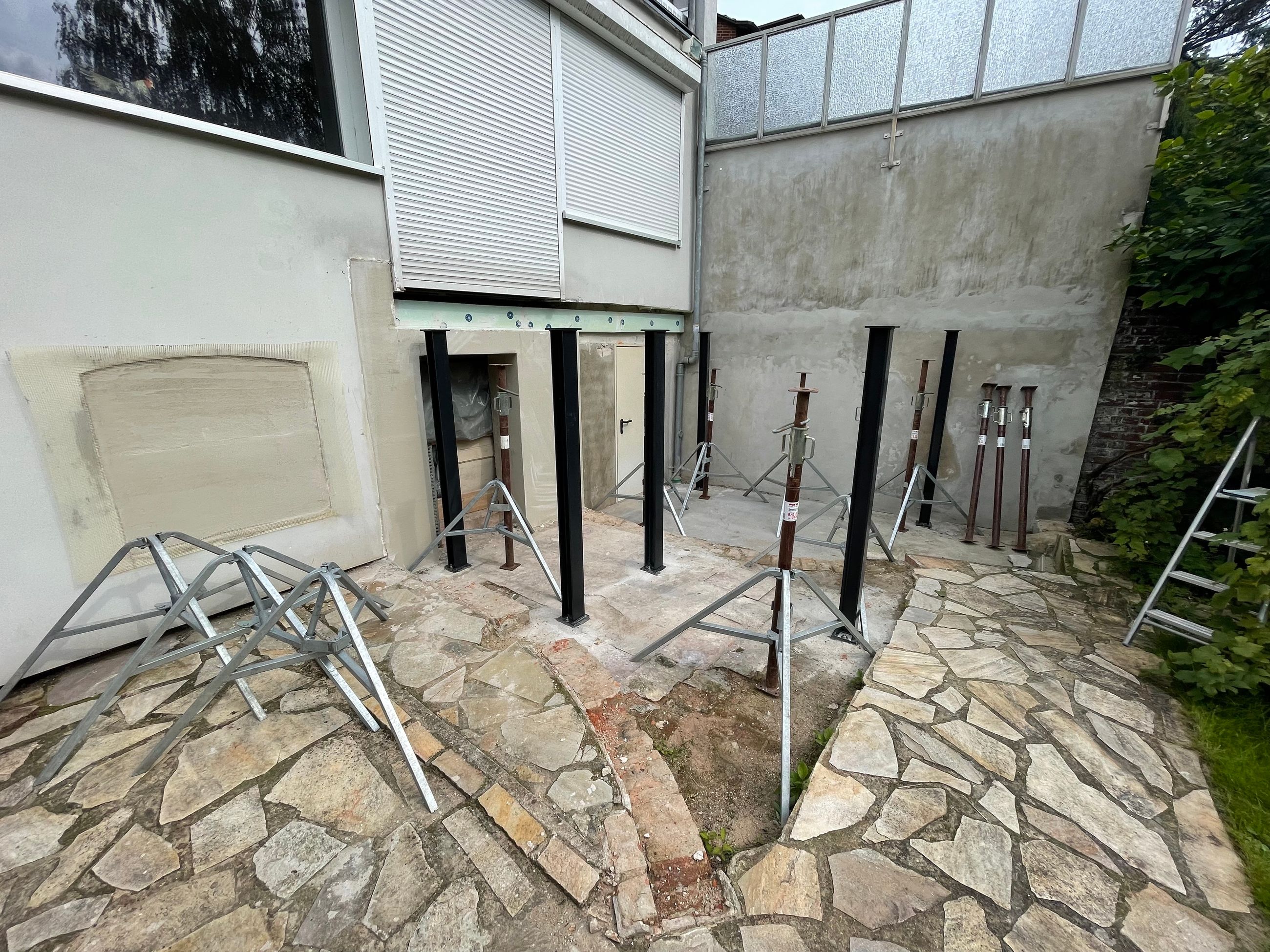 Terrasse im Umbau mit vorbereiteten Flächen, Stützen und angrenzender Gebäudesanierung