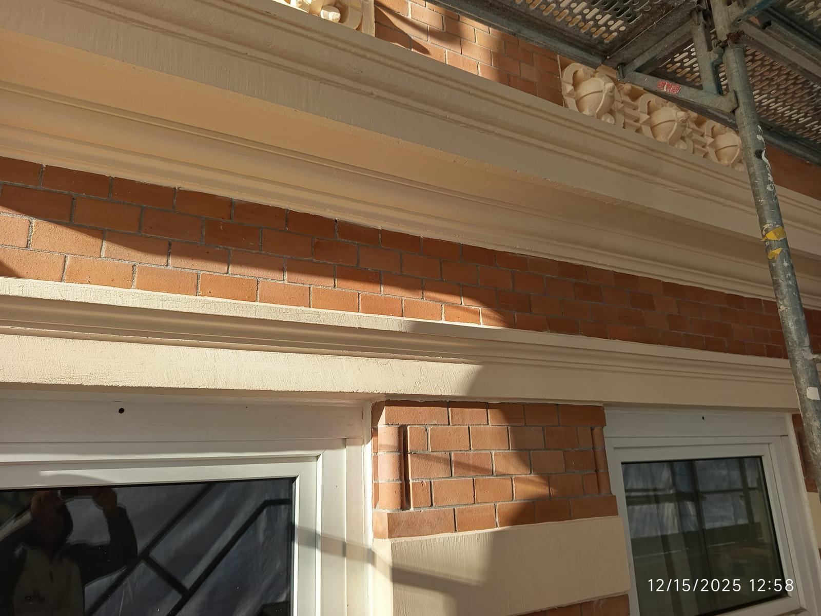 Fassade während der Sanierung mit bearbeiteter Oberfläche und sichtbaren Arbeiten an der Außenwand