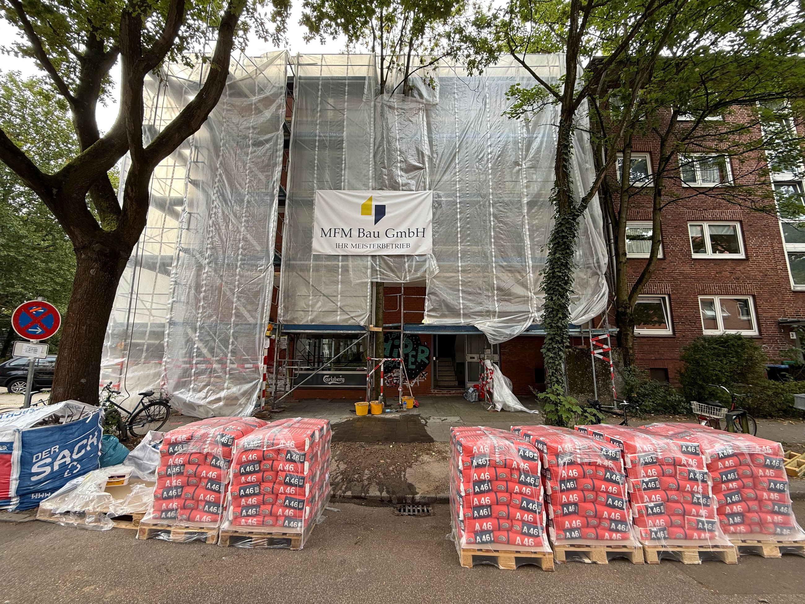 Außenansicht einer Gebäudewand während der Sanierung mit Gerüst und laufenden Arbeiten an Balkonen