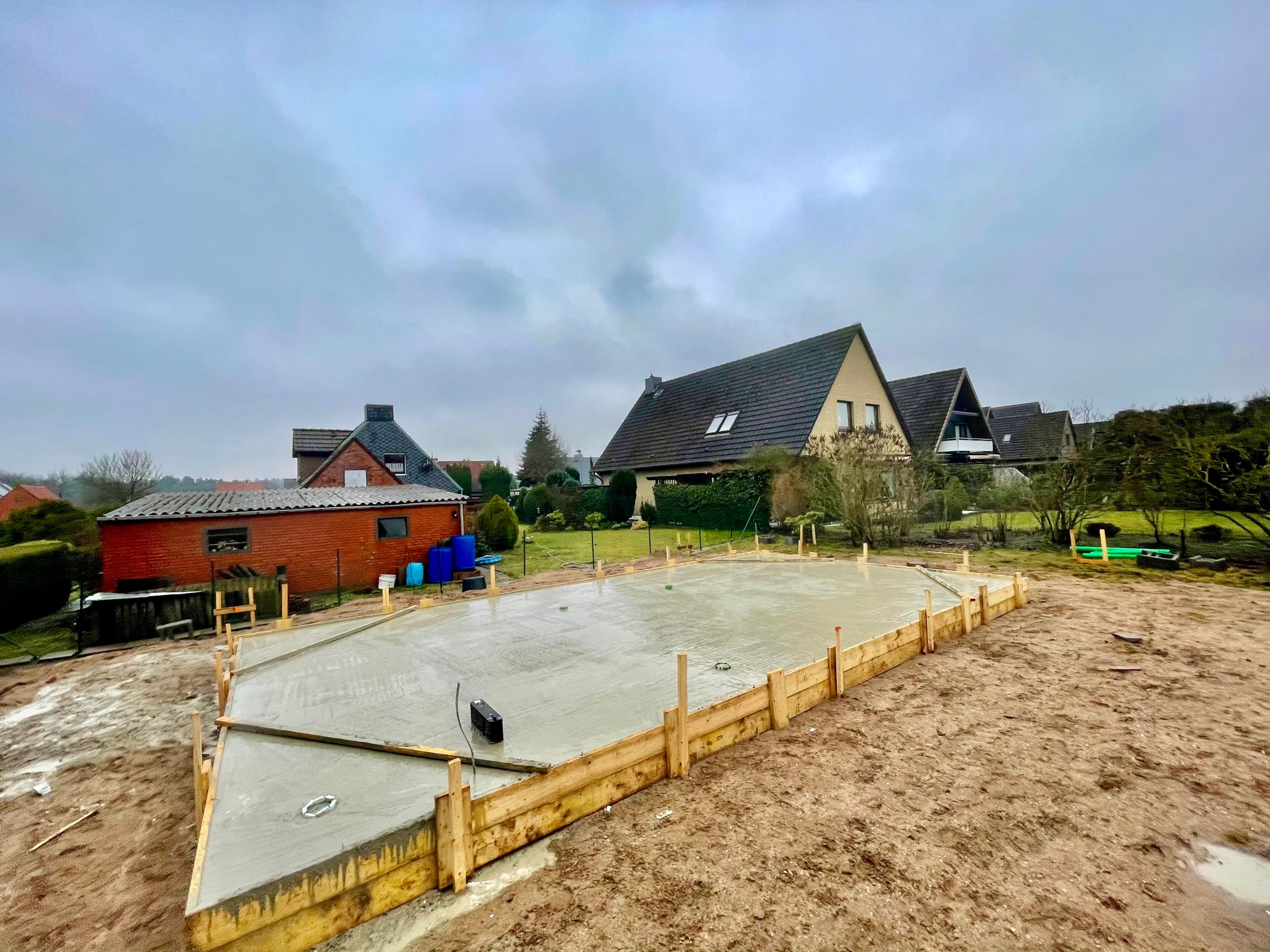 Hausbau in der Anfangsphase mit neuem Mauerwerk und vorbereiteter RohbaustrukturAußenbereich mit neu aufgebautem Basisboden als Vorbereitung für weitere Maurerarbeiten