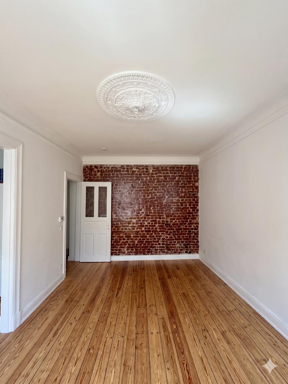 Altbauzimmer mit weißen Wänden, Stuckrosette und Dielenboden