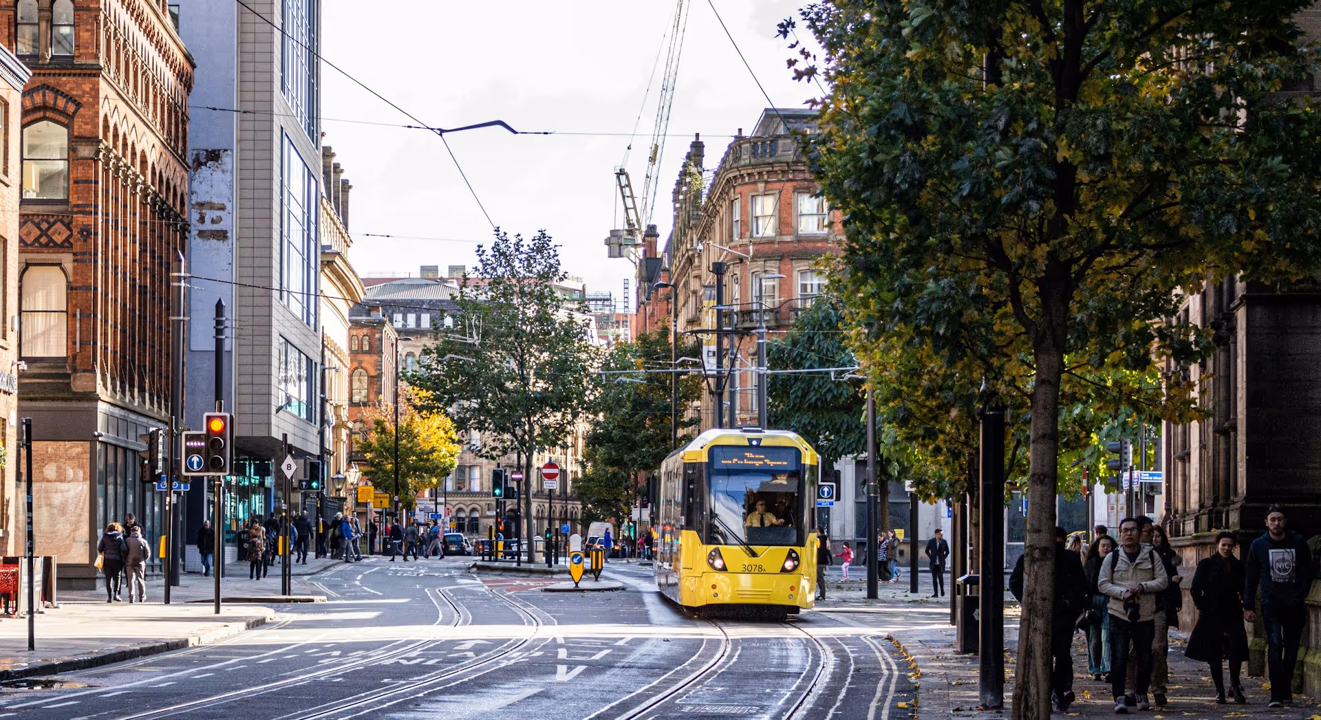 A city centre with a yellow tram on Princess Street, Manchester, UK