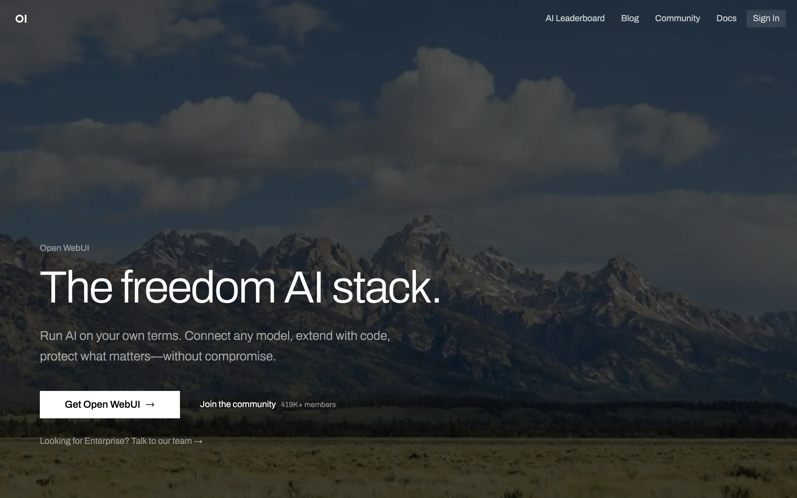 Open WebUI landing page with a fullscreen mountain photo background and the headline "The freedom AI stack" over a dark overlay