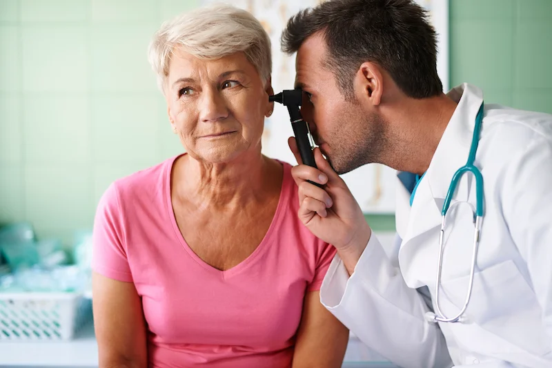 Médecin examinant l’oreille d’une femme âgée
