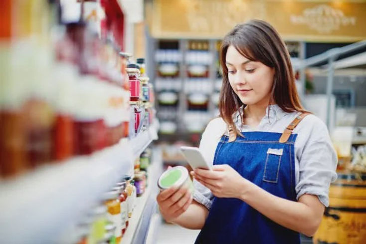 A person scanning a product from a shelf in a supermarket