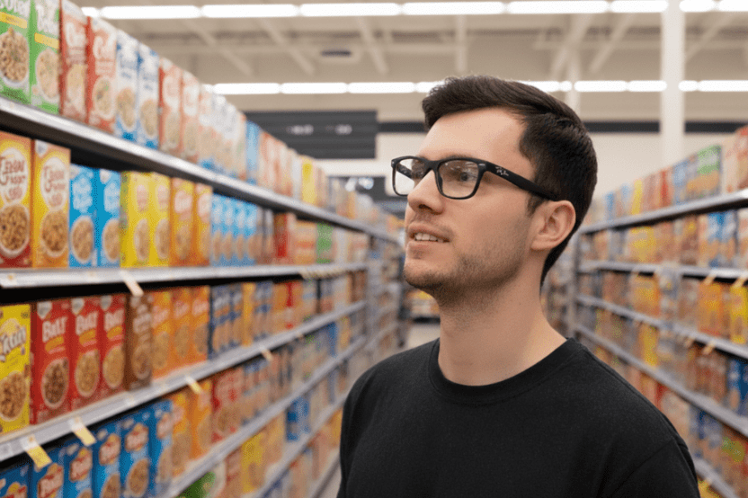 Man wearing Ray-Ban smart glasses looking along a supermarket cereal aisle