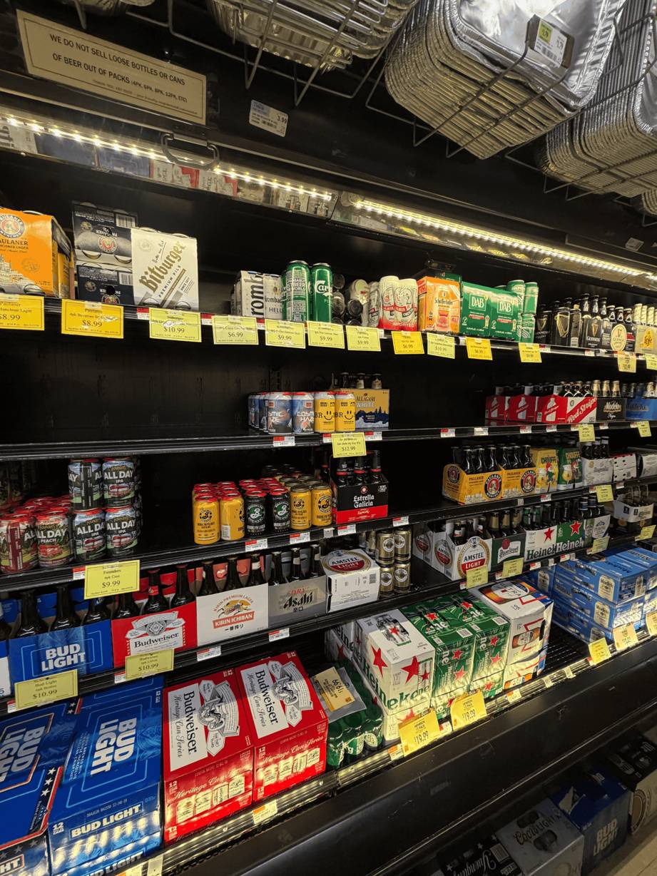 A photo of an open fridge in store showing products with some shelf areas empty of products