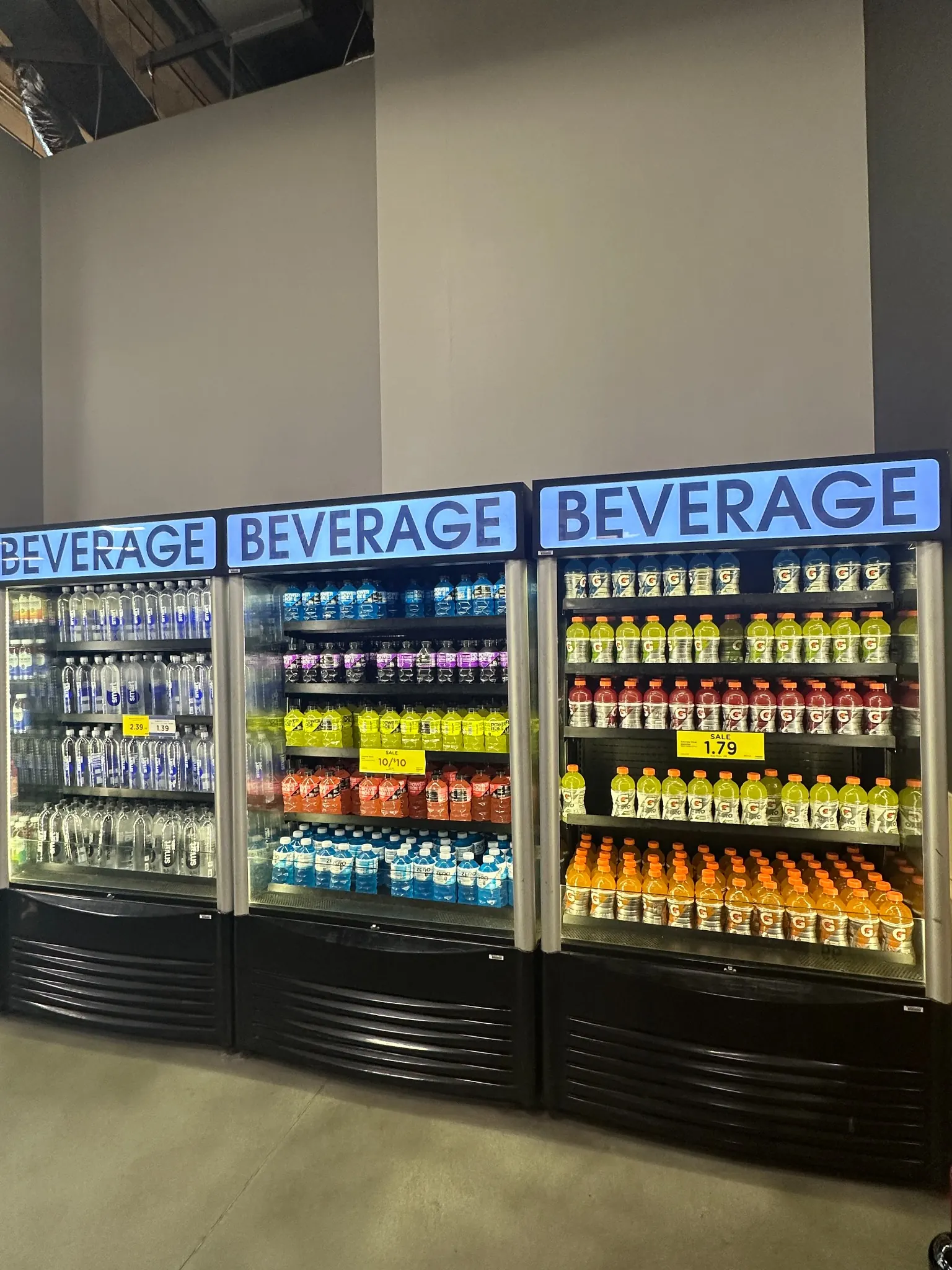 Pristine, brightly lit retail beverage coolers with neatly arranged water, sports drinks and soft drinks.