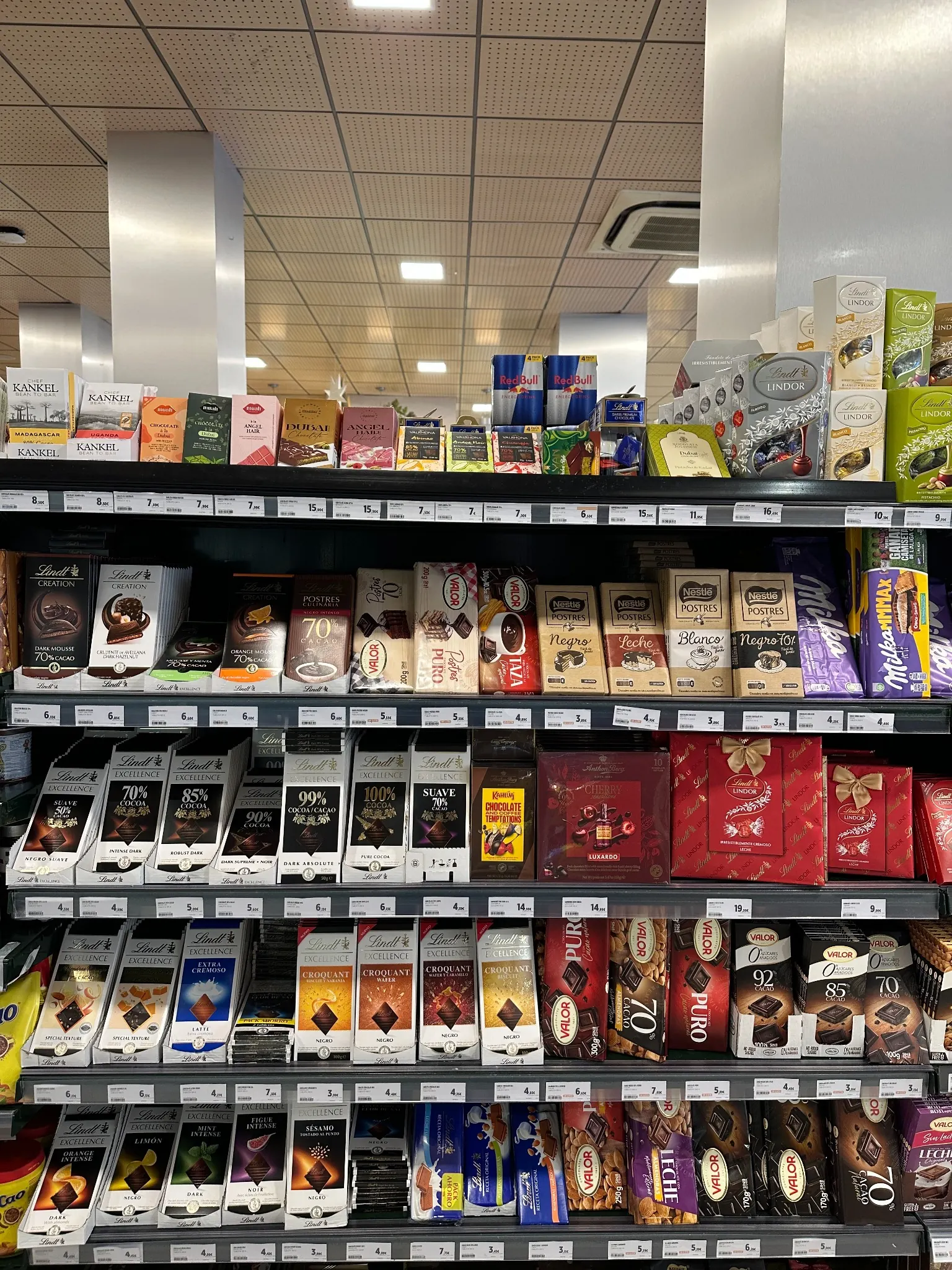 Dense premium supermarket chocolate display featuring multiple brands, products and euro price labels.