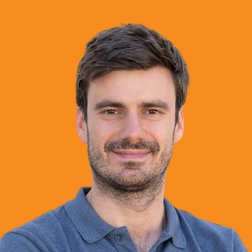 Headshot of a Neurolabs team member in a blue polo shirt against an orange background