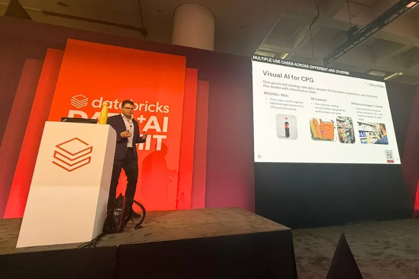 Speaker presenting a 'Visual AI for CPG' slide on stage at the Databricks Data + AI Summit