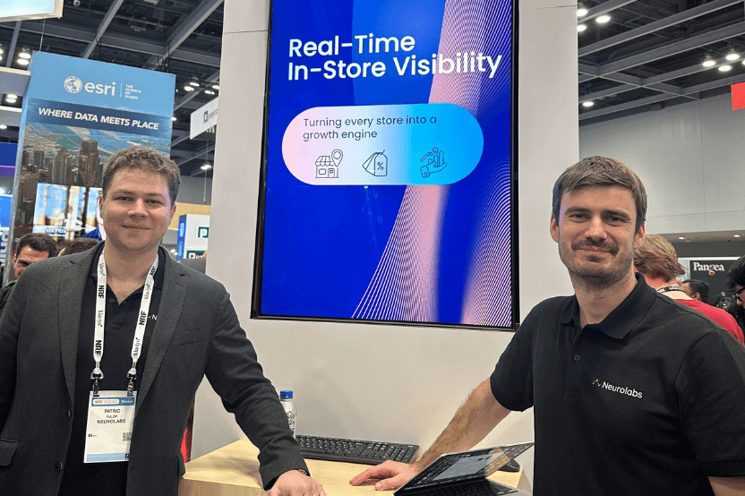 Two Neurolabs staff at the company's NRF trade show booth beside a screen reading Real-Time In-Store Visibility