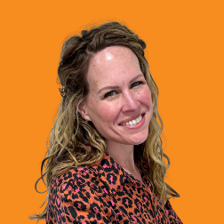 Headshot of a smiling woman with long wavy hair in a leopard-print top on an orange background