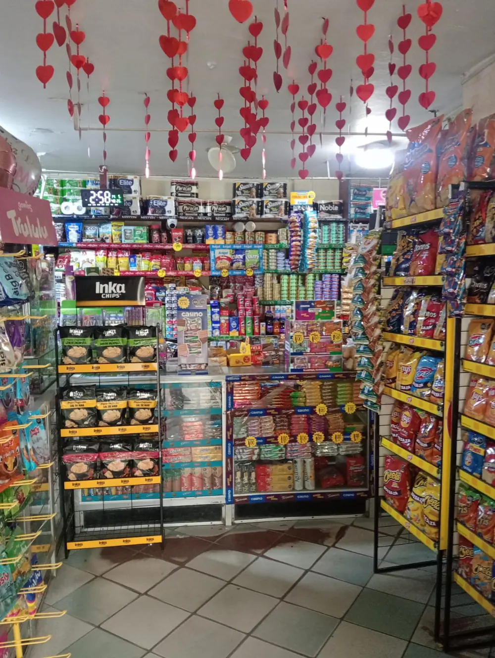 Interior of a compact convenience store with snacks, sweets and drinks lining every wall.