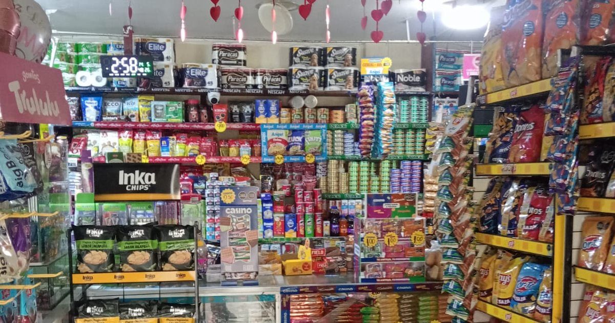 Crowded small independent store in Latin America with snacks, sweets and drinks on every shelf under hanging decorations.