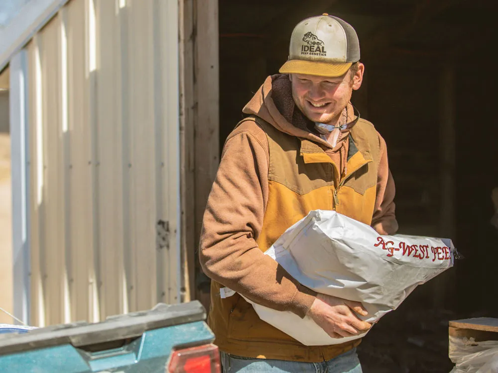 rancher loading feed bag into truck